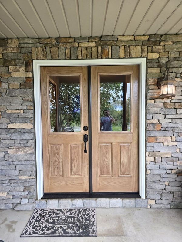 New wood double entry doors with glass panels set in a stone veneer front