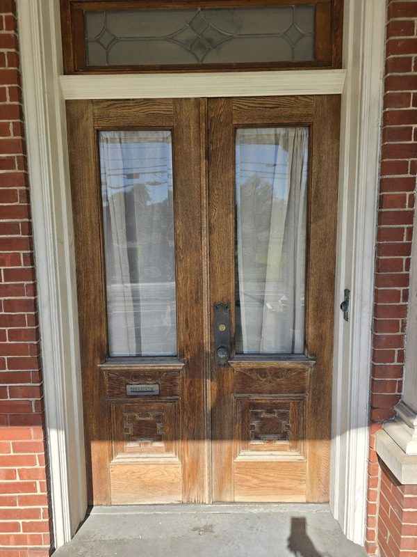 Historic-style wood double entry doors with glass panels and transom in a brick front